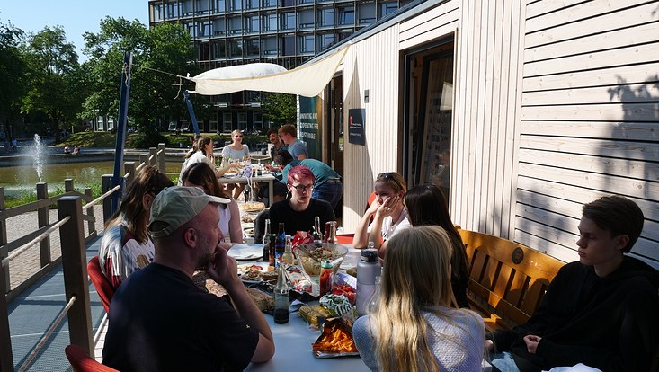 Blick auf Menschen, die vor dem Tiny House essen und sich unterhalten.