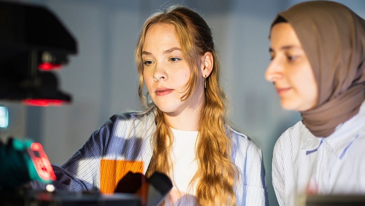 Zwei Studierende an einem Mikroskop im CUI Laserlabor