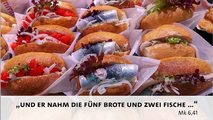 Viele Fischbrötchen mit einem Schriftzug "Und er nahm die fünf Brote und zwei Fische..." von Mk 6,41 unten im Bild.