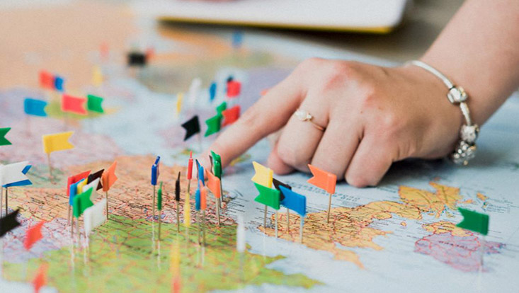 Eine Hand zeigt auf eine Landkarte mit vielen Fähnchen