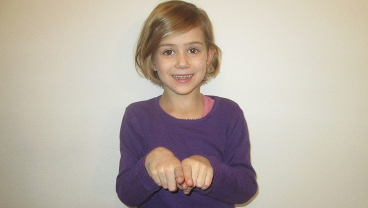 Ein Mädchen zeigt mit ihren Händen eine Gebärde.