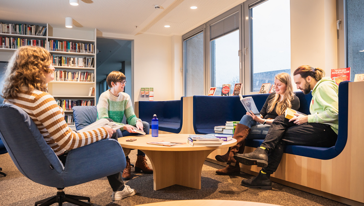 Vier Studierende sitzen in einer offenen Workshop-Zone in der Bibliothek für Geisteswissenschaften