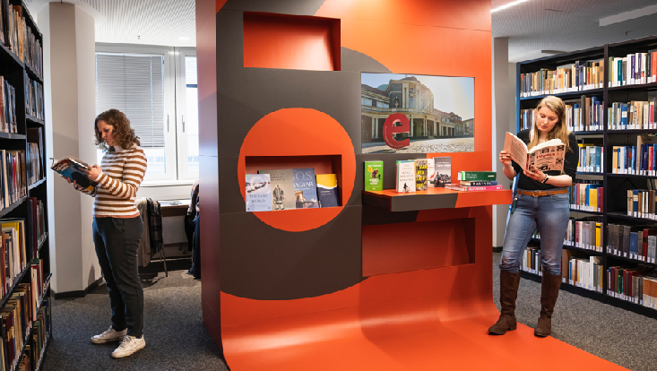 Zwei Studierende stehen in der Bibliothek im Philturm und lesen