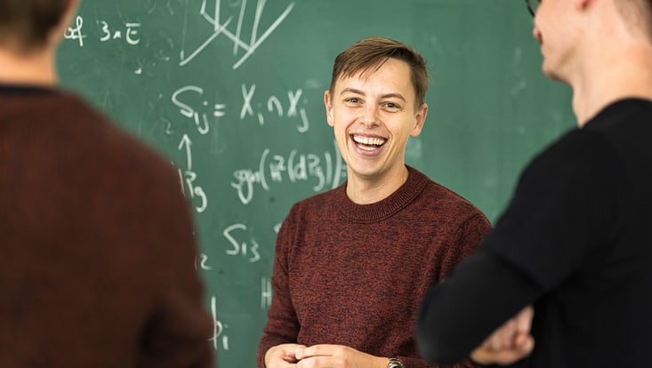 Studierende vor einer Kreidetafel.