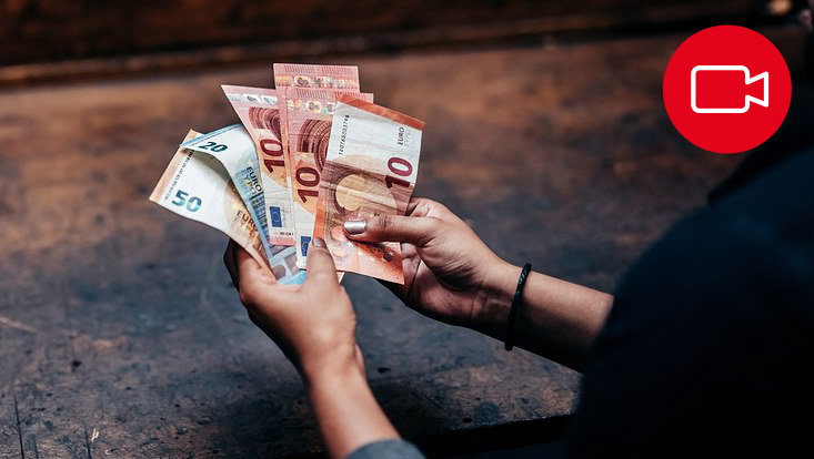 Blick auf die Hände einer Person, die Geldscheine in der Hand hält.